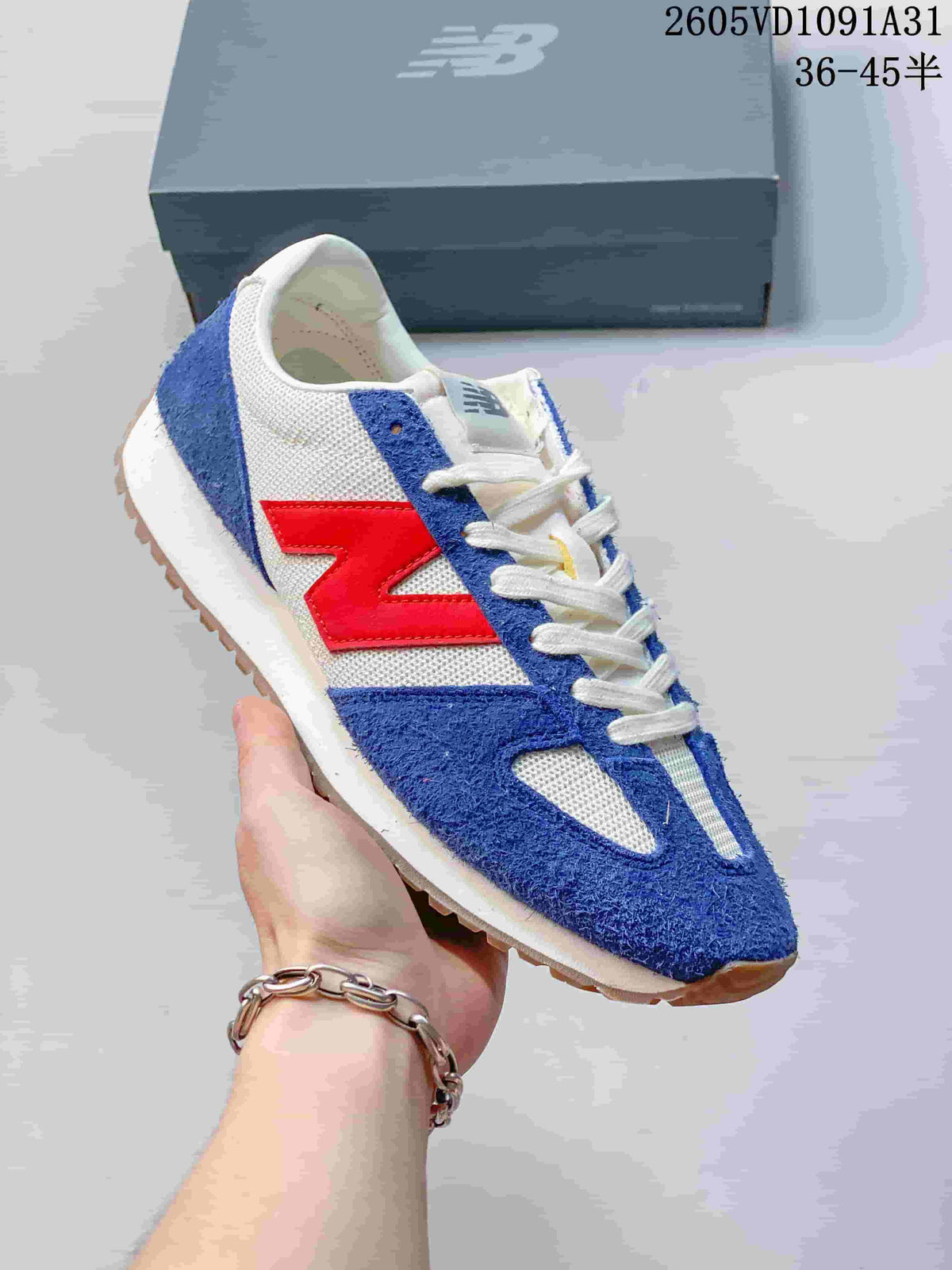 Angled side view of the blue, white, and red New Balance sneaker