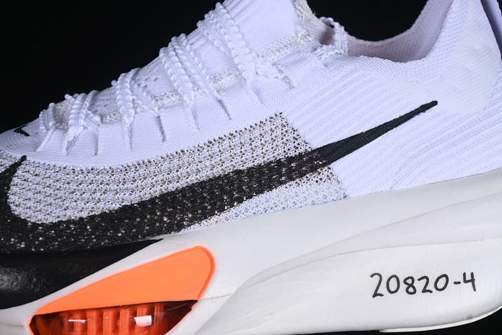 Close-up of the black Swoosh, white upper and orange midsole accent