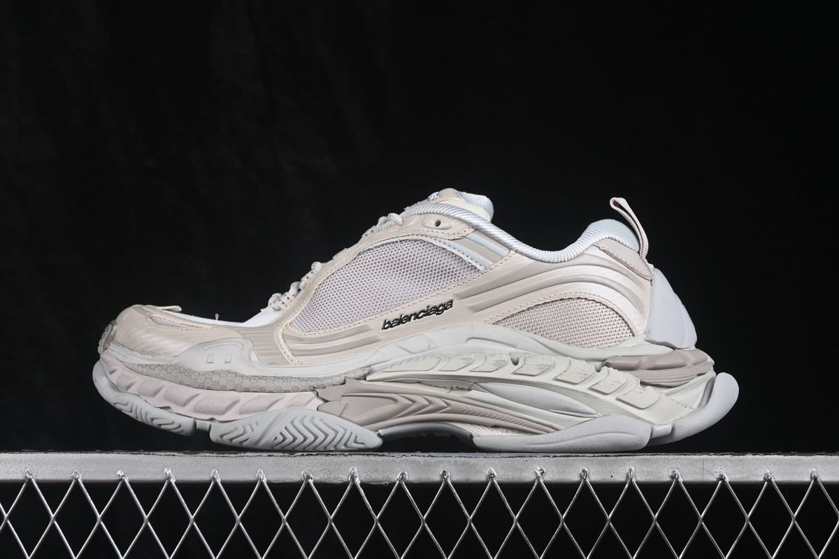 Side profile of cream and white Balenciaga Triple S 2 sneakers showing layered panels, mesh sections and a chunky outsole.