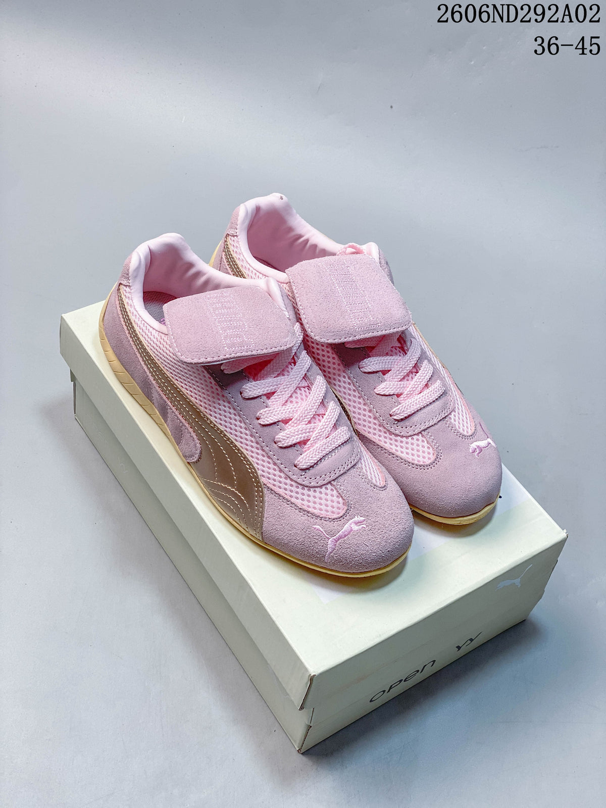 Pink Puma Speedcat The Open YY sneakers with a metallic-look side stripe and fold-over tongue panels, shown on a shoebox.