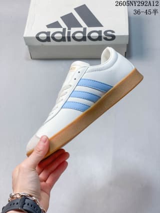 Side view highlighting the white upper, light blue stripes, and gum-colored rubber sole.