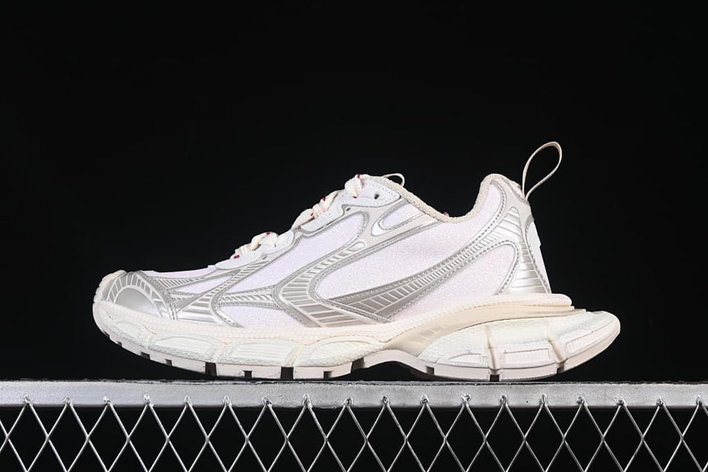 Side view of beige and silver Balenciaga 3XL sneakers against a black background