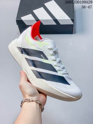 Angled side view of the shoe showing the white textured upper, black stripes, red collar accent, and white sole.