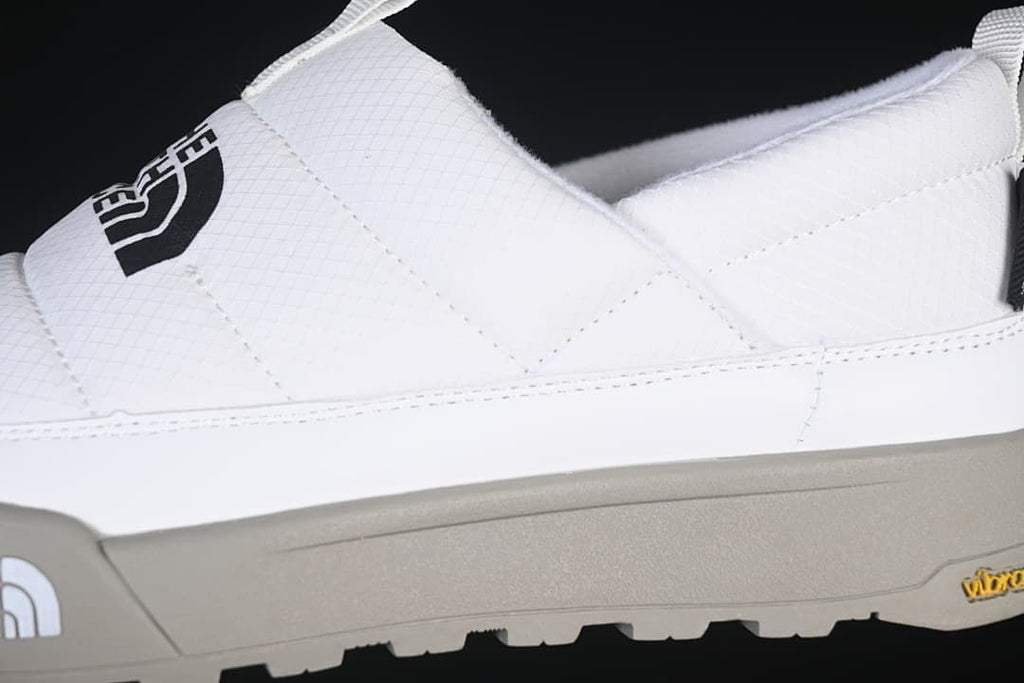 Side close-up of the white upper, logo, and grey outsole