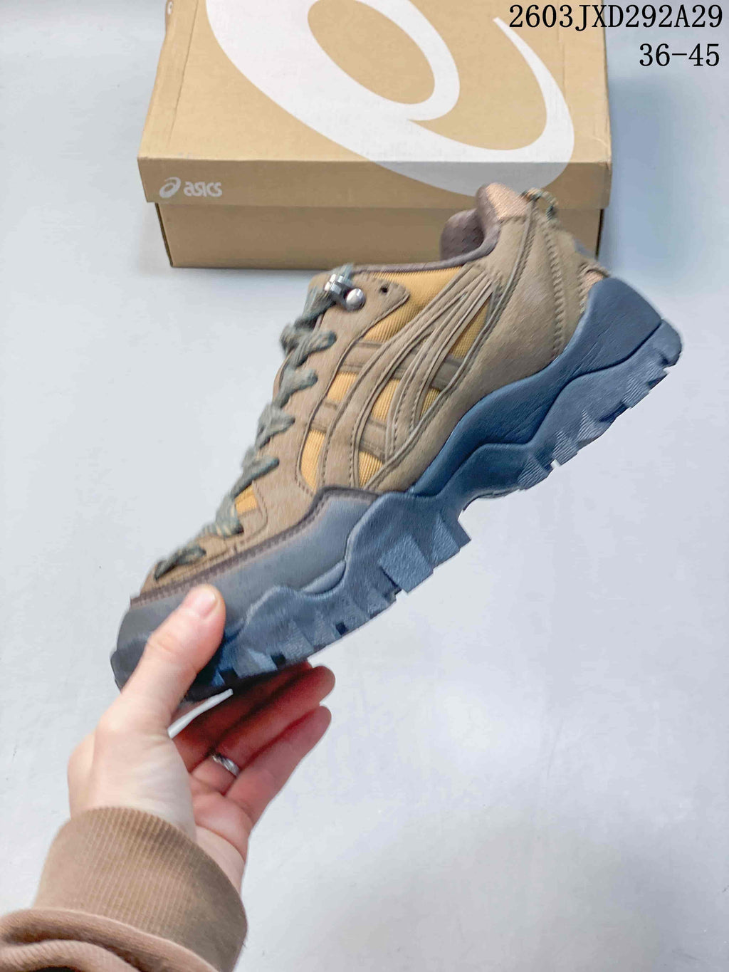 Side view of a tan and brown ASICS Gel-Pickax sneaker with a dark, rugged-looking outsole.