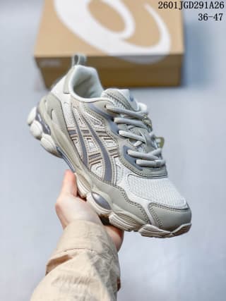 Light-gray and white ASICS GEL-NYC RGD sneaker held in hand; image text shows code 2601JGD291A26 and sizes 36–47.