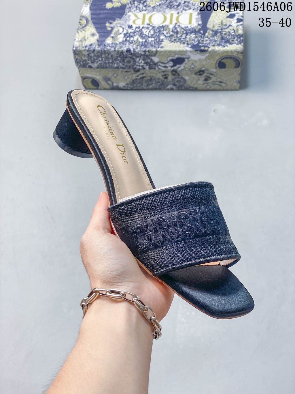 Angled view of a dark navy embroidered mule sandal with a square toe and cylindrical heel