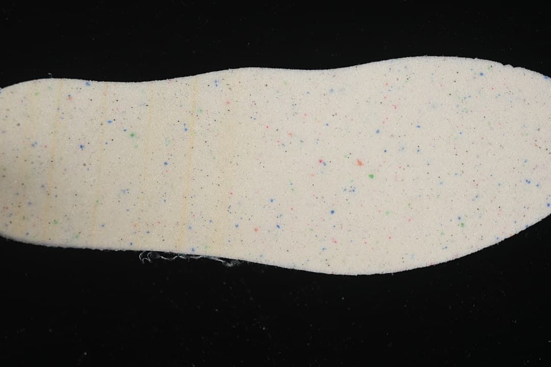 Close-up of a light-colored shoe insole with scattered colored flecks