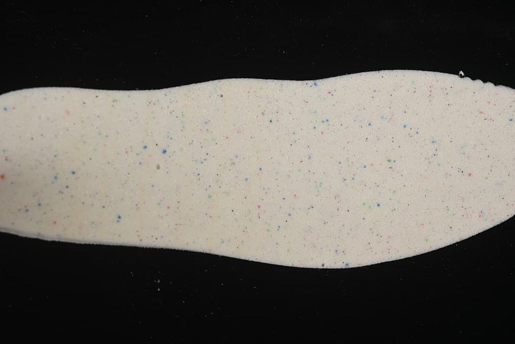 Removable insole showing a light-colored surface with multicolor speckles.