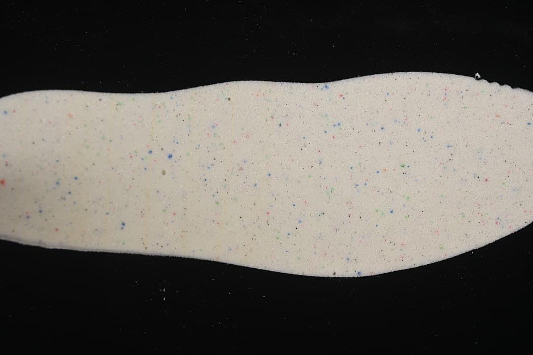 Removable insole showing a light-colored surface with multicolor speckles.