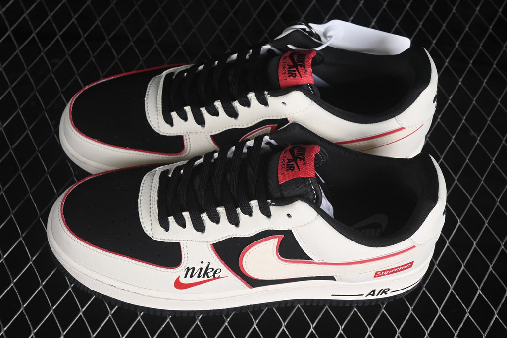 Pair of Nike Air Force 1 Low sneakers showing the white, black and red color scheme, black laces and side branding.