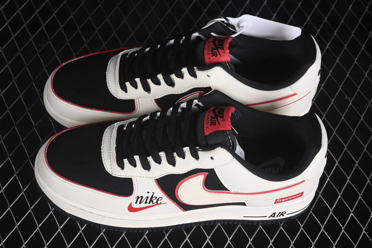 Pair of Nike Air Force 1 Low sneakers showing the white, black and red color scheme, black laces and side branding.