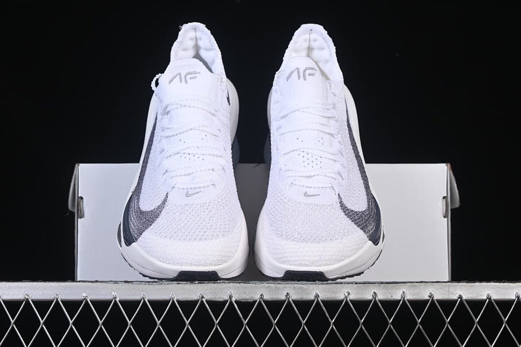 Front view of the pair of white racing shoes resting on a box