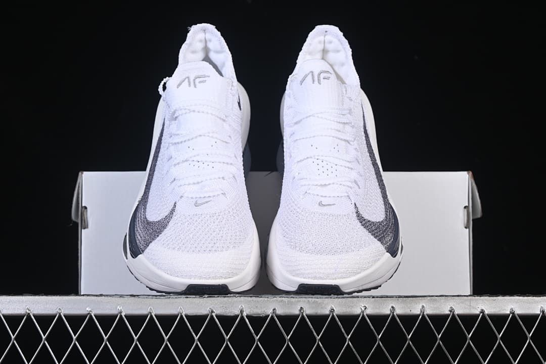 Front view of the pair of white racing shoes resting on a box
