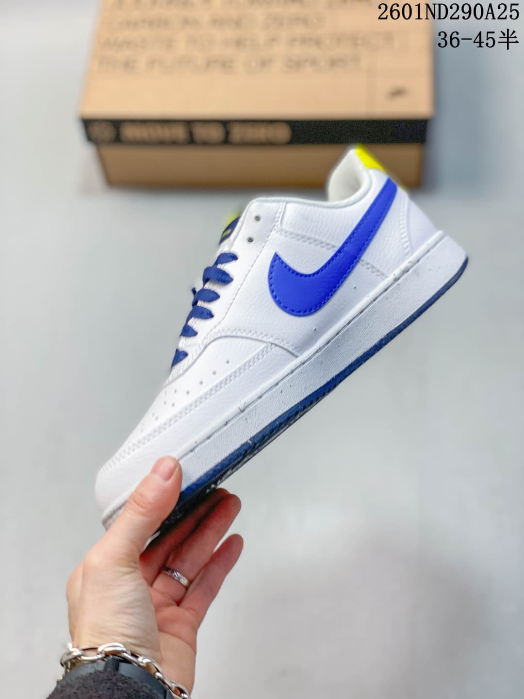 Side view of the low-top white sneaker with a blue Swoosh and blue outsole accents.