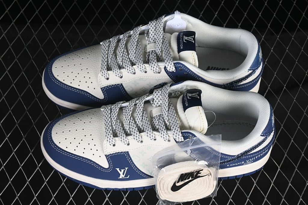 Top view of a white and navy pair of low-top sneakers with patterned panels and an additional pair of white laces.