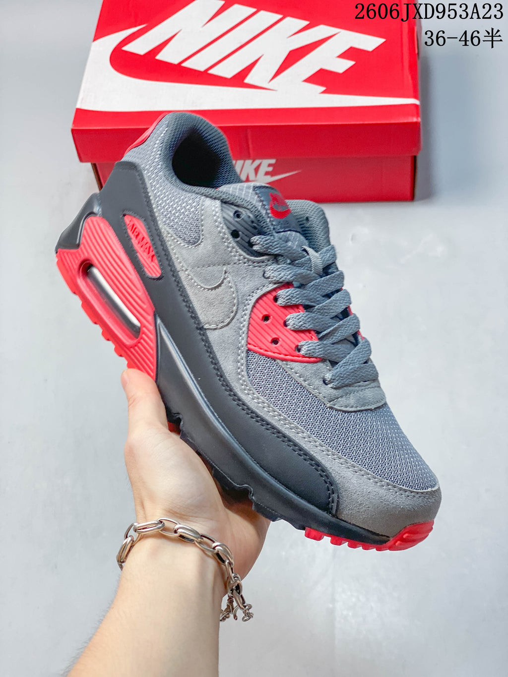 Angled side view of a gray and red Nike Air Max 90 sneaker