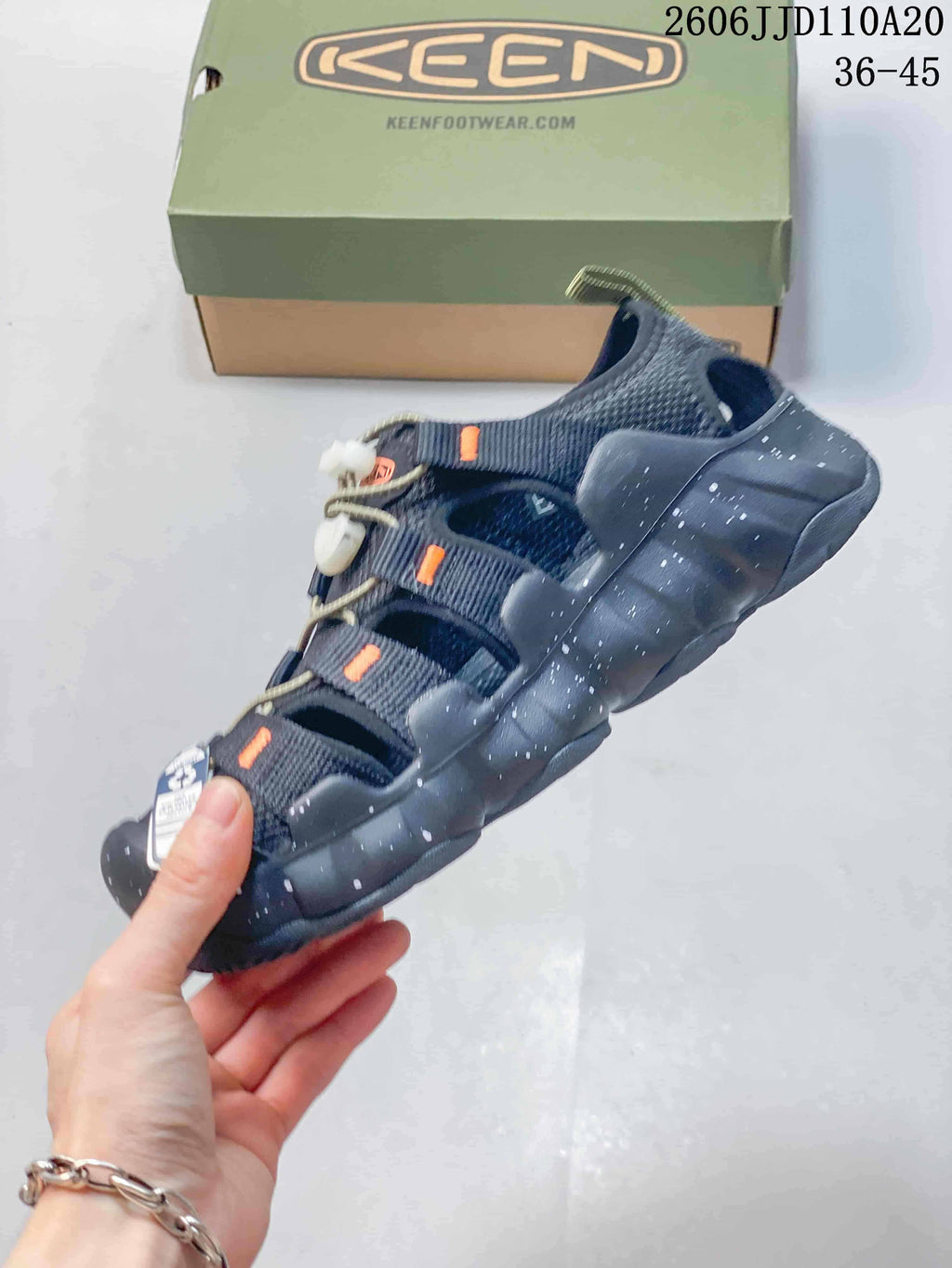 Side view of a dark navy sandal with cord closure and a thick speckled outsole.