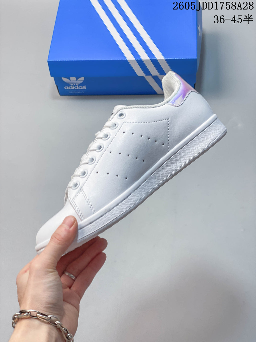 Side profile of a white low-top sneaker with perforated panels and iridescent heel detail