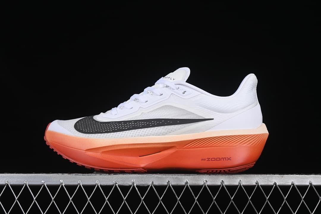 Side profile of white Nike Zoom Fly 6 running shoes with black swoosh and coral-orange sole
