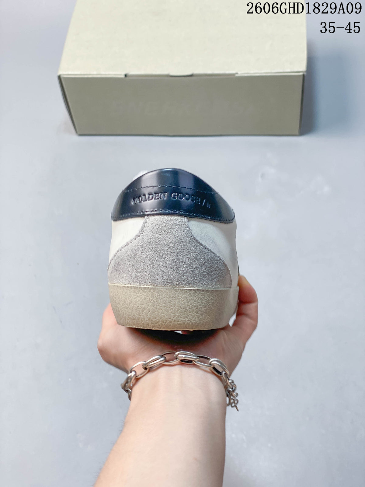 Rear view of sneaker with a dark blue heel tab and gray suede-like heel panel