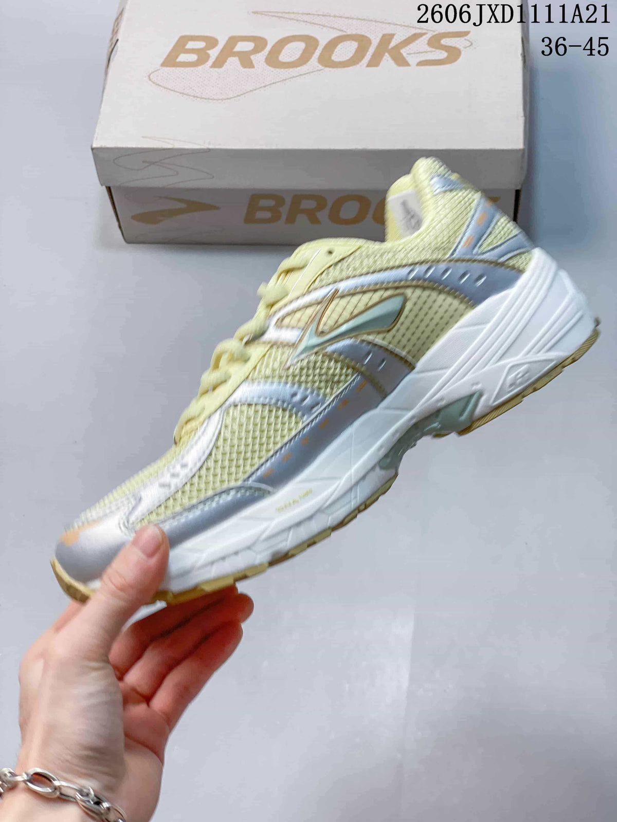 Side view of a pale yellow and silver-toned Brooks running sneaker