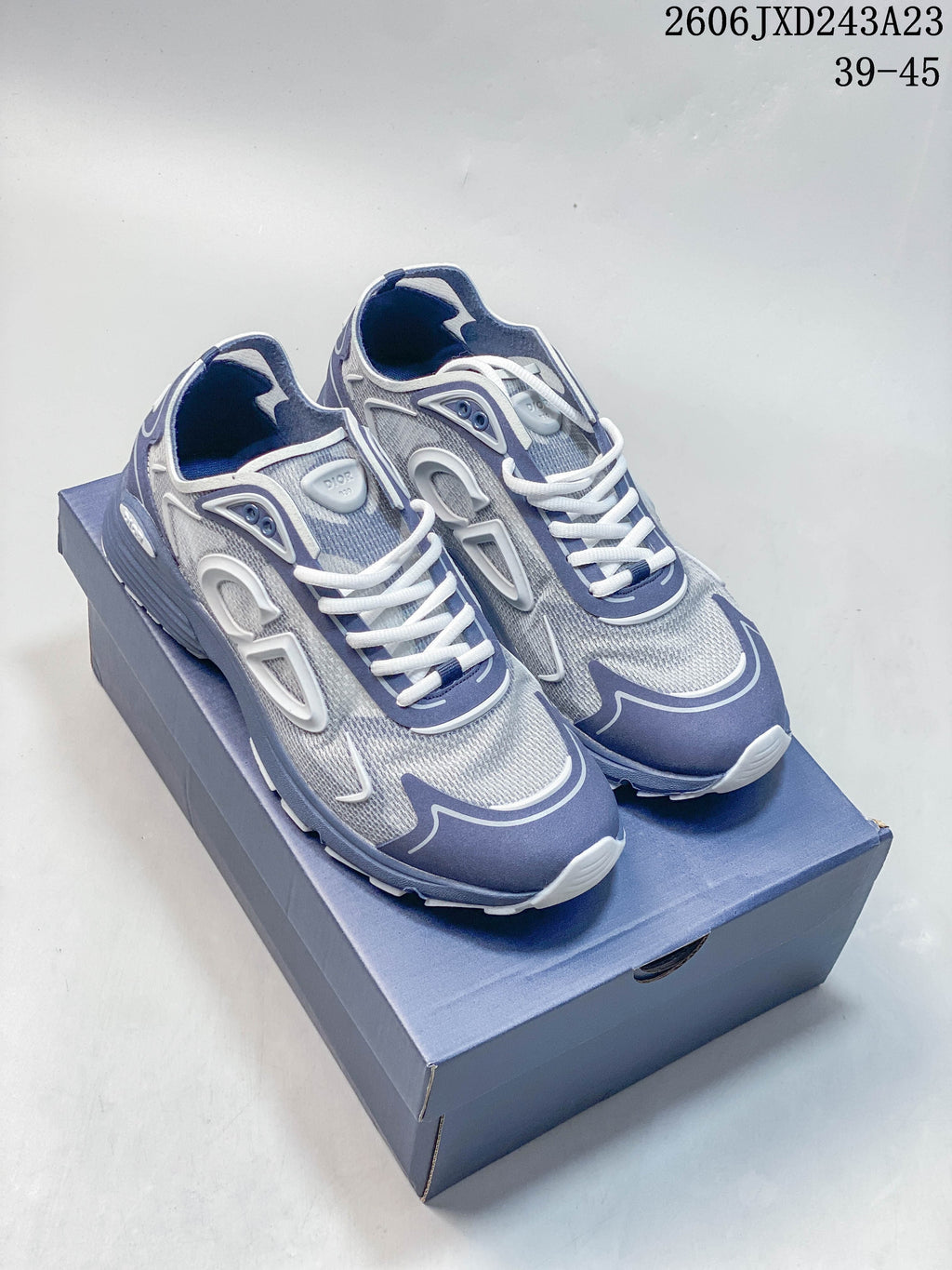 Pair of gray, blue, and white Dior B30 low-top sneakers on a box