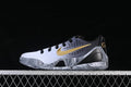 Side view of a white, gray, black, and gold low-top Kobe basketball shoe