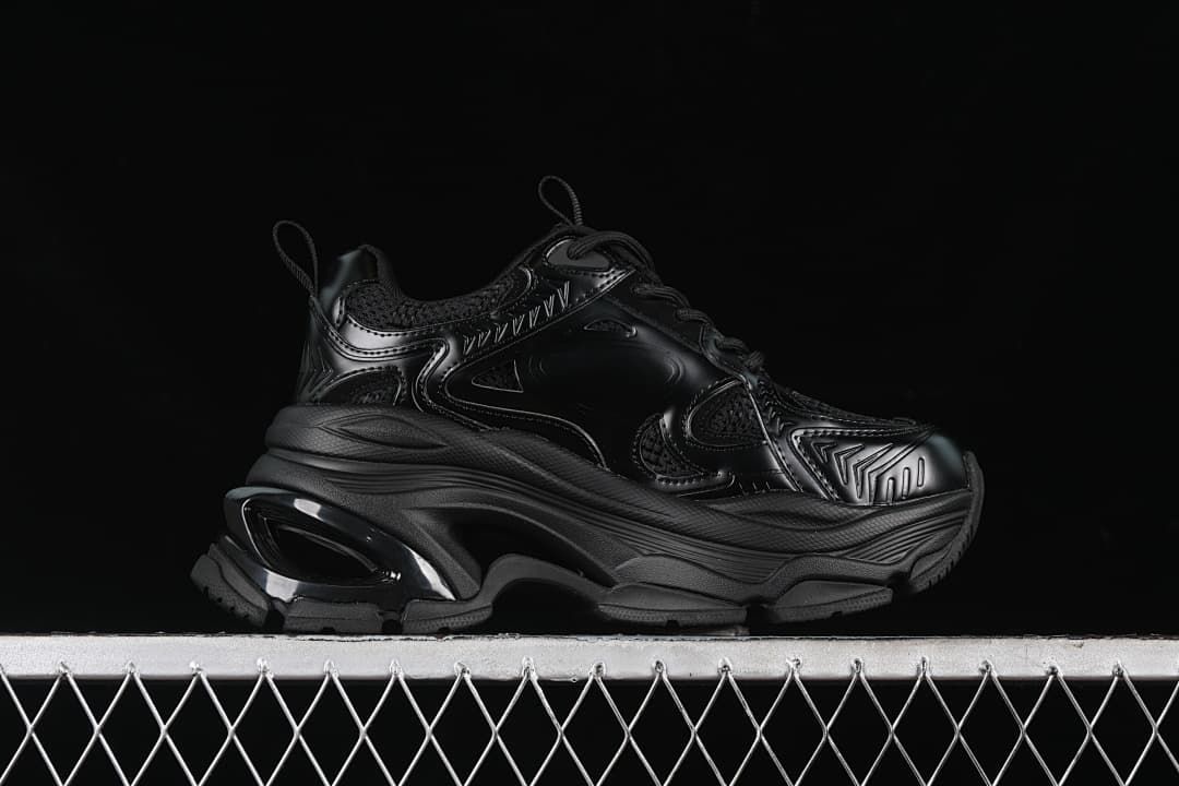 Side profile of the black sneaker showing its thick, sculpted sole.