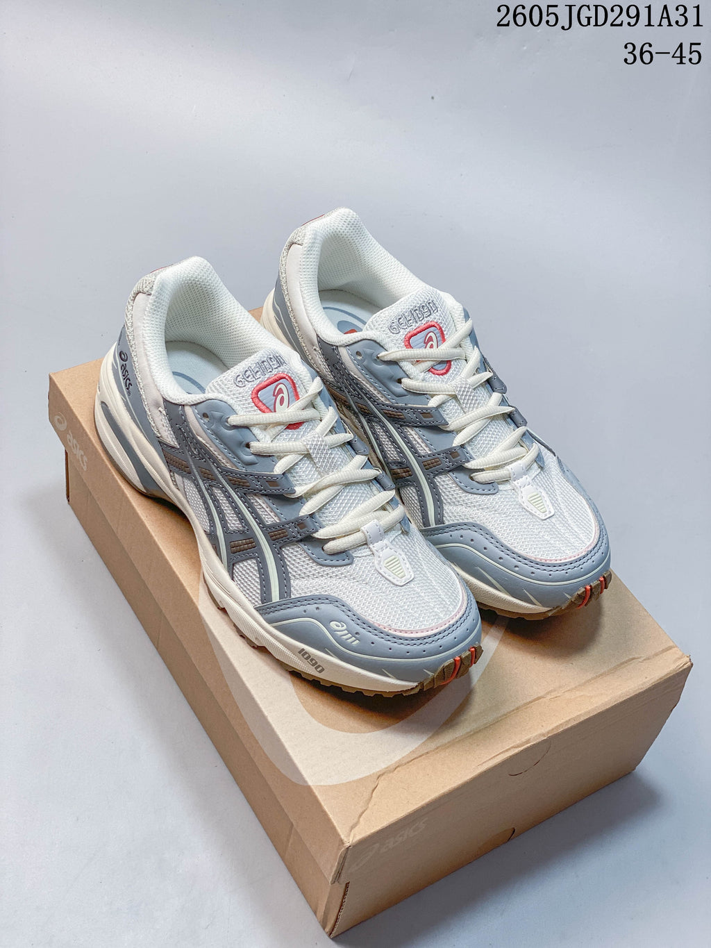 Pair of white and blue-gray ASICS lace-up sneakers with red accents, shown on a shoe box.