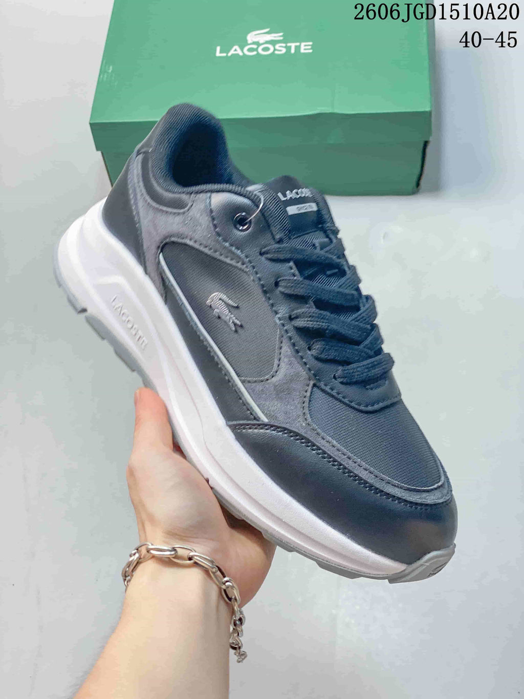 Angled view of a grey and navy Lacoste sneaker with a crocodile emblem and white midsole.