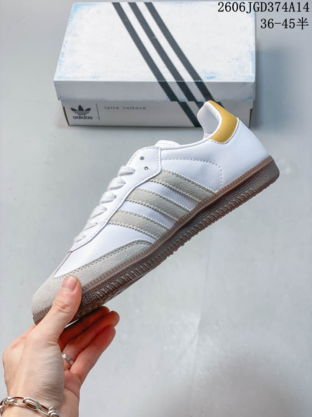 Side view of the white low-top sneaker with gray stripes, gray overlays, and a brown-toned outsole