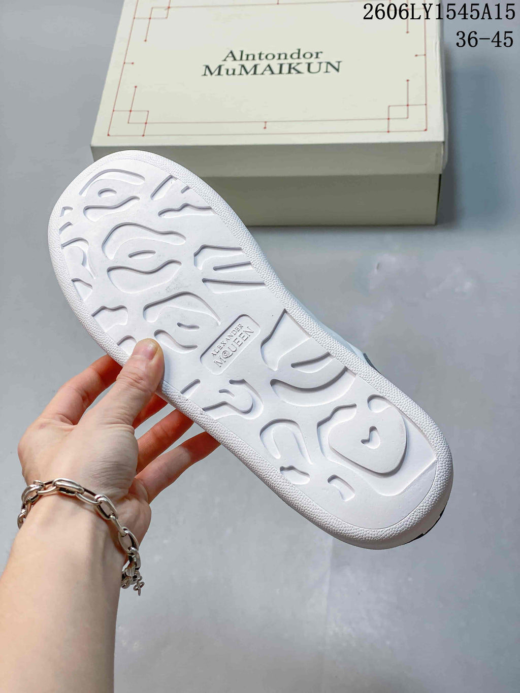 Underside of a white sneaker showing a patterned tread.