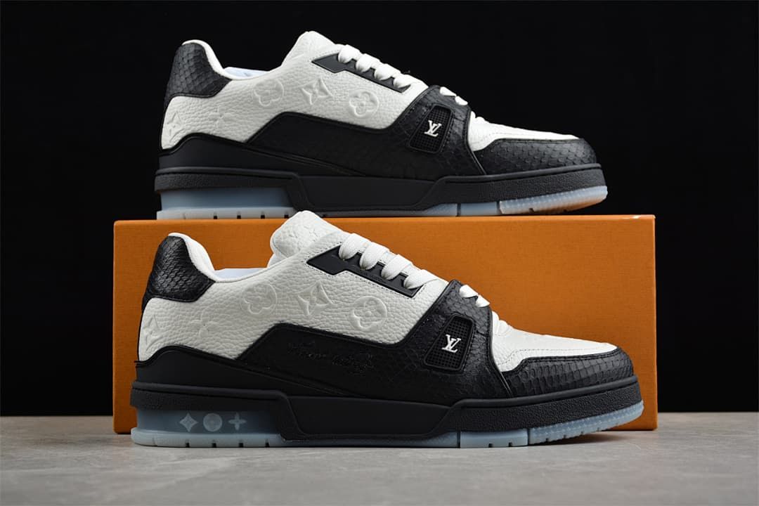 Pair of black and white sneakers displayed in front of an orange shoebox.