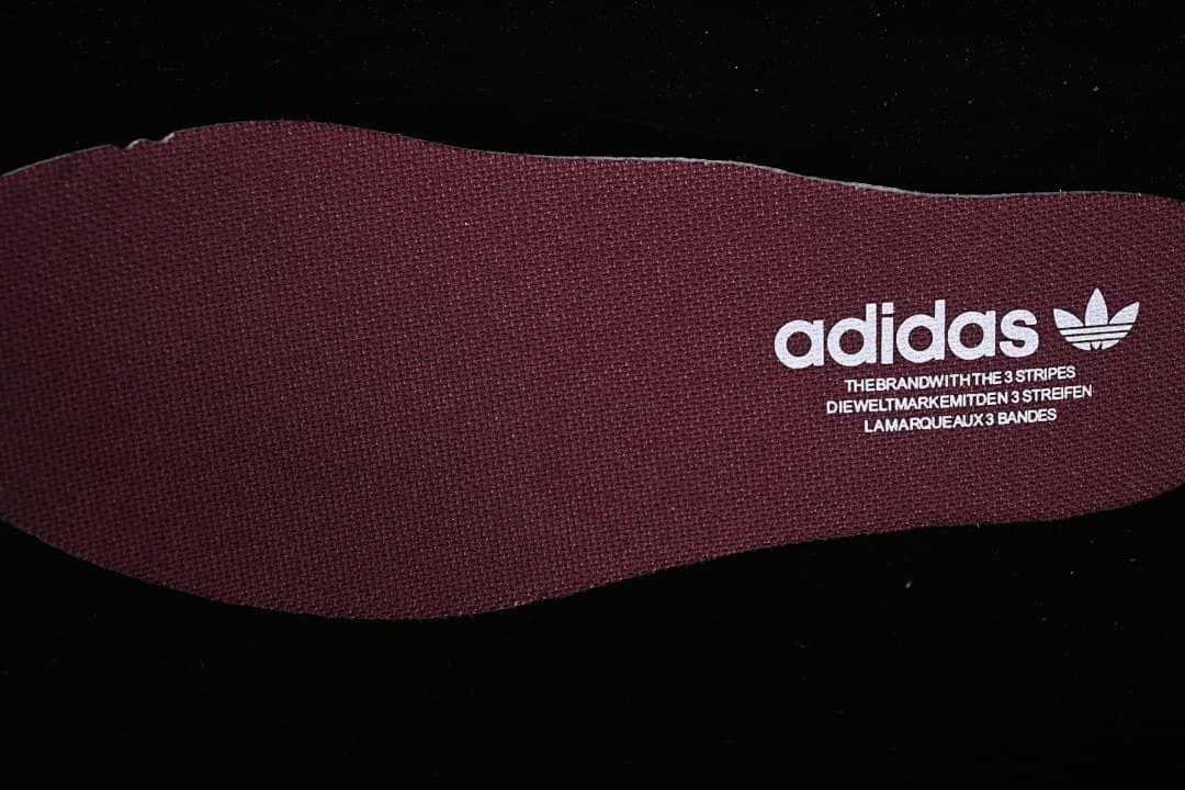 Close-up of a burgundy insole with Adidas Trefoil branding