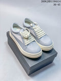Pair of pale gray and white Rick Owens Vintage Sneaker low-tops with cream laces, shown on a dark shoe box