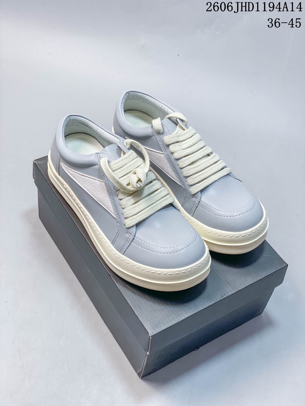 Pair of pale gray and white Rick Owens Vintage Sneaker low-tops with cream laces, shown on a dark shoe box