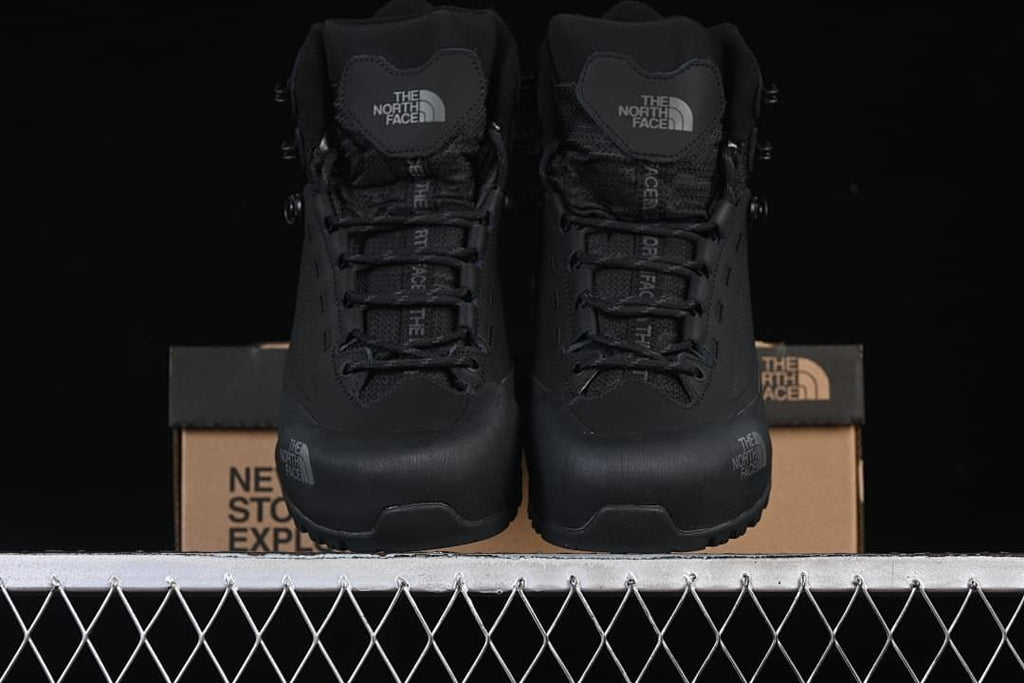 Front view of a pair of black lace-up mid boots.
