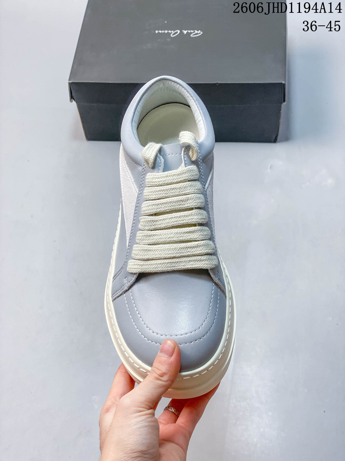 Top view of a pale gray sneaker with broad cream-colored laces