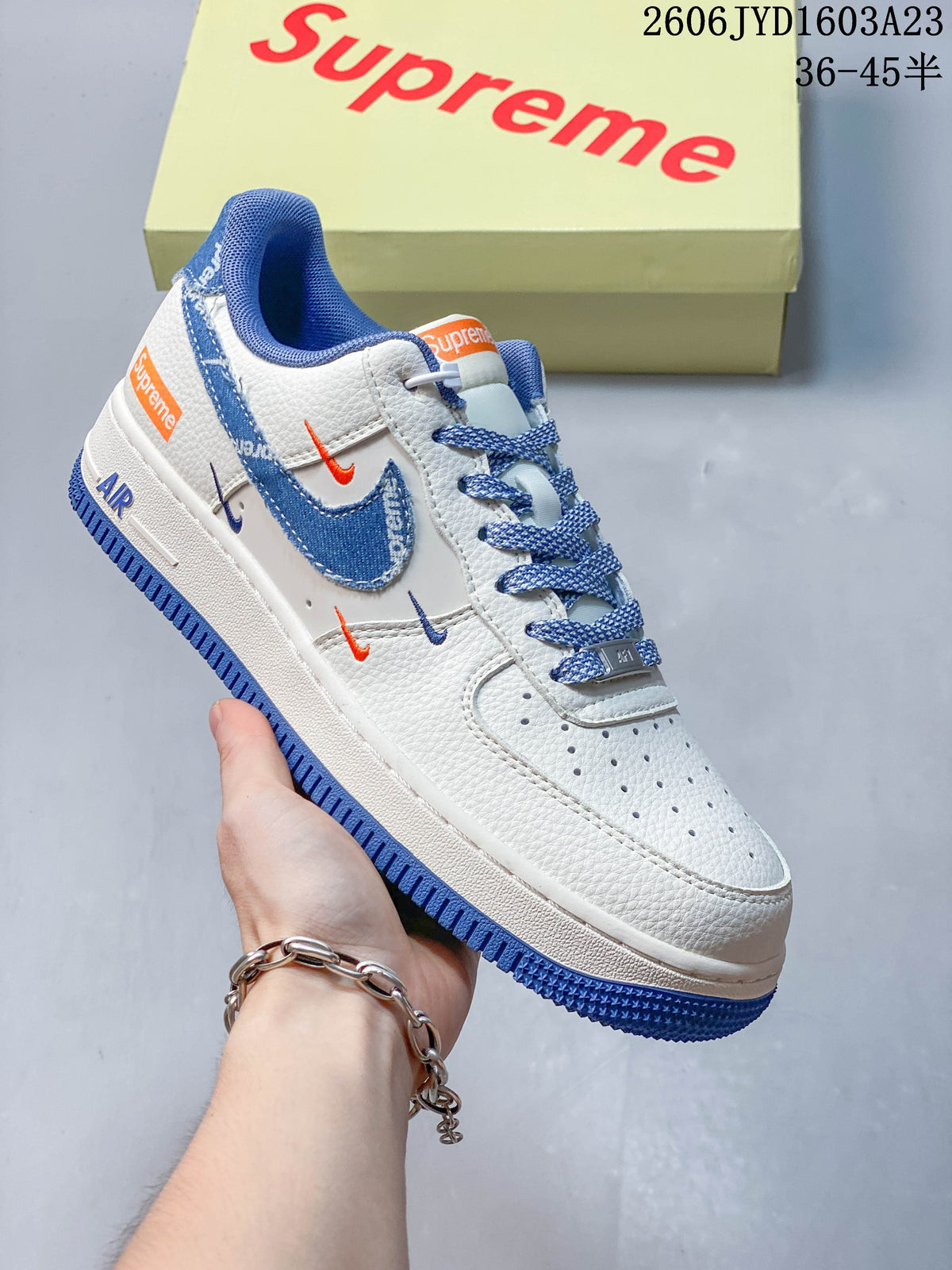 Angled view of a white low-top sneaker with blue details and small contrasting swoosh accents