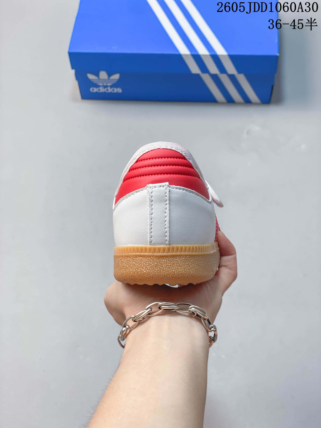 Rear view of the white sneaker showing its red heel detail and gum-colored sole