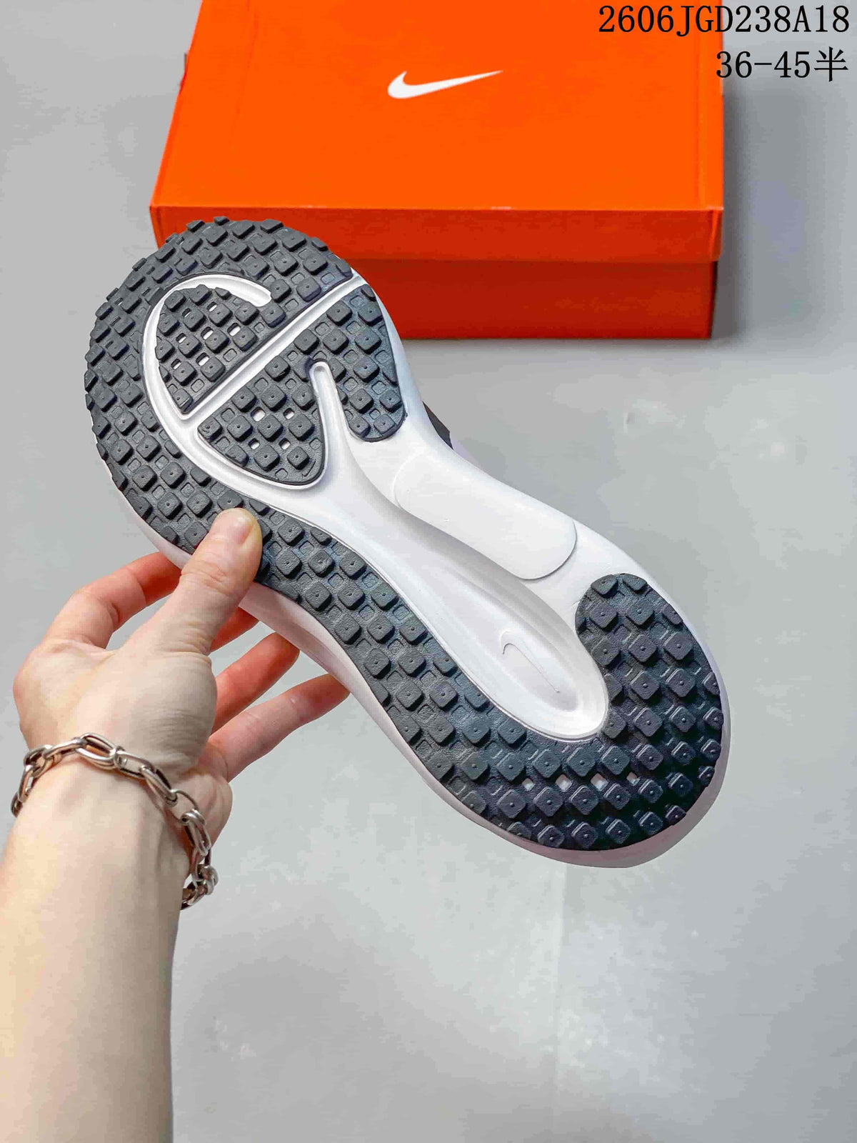 Underside of a running shoe showing a dark patterned outsole and white midsole