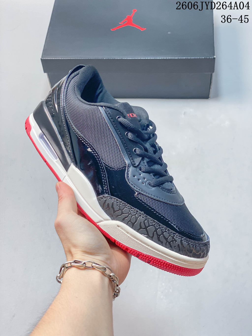 Side profile of the sneaker showing its dark upper, white midsole, and red outsole