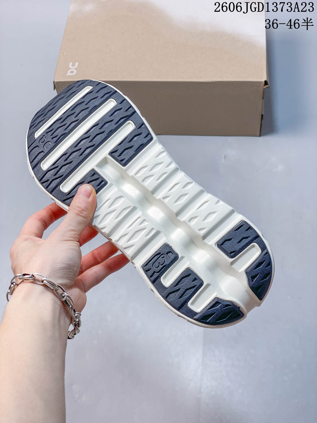 Underside of a sneaker showing dark tread sections and an off-white sole