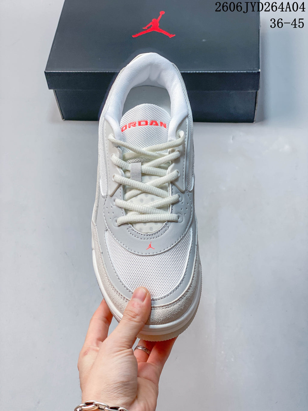 Top view of a lace-up Jordan sneaker with mesh-look panels and red tongue lettering