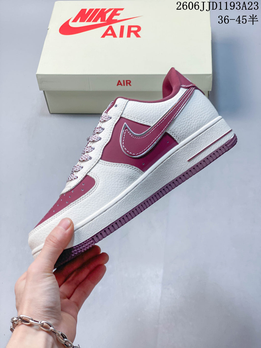Side view of a white and burgundy low-top sneaker with a contrasting Swoosh.
