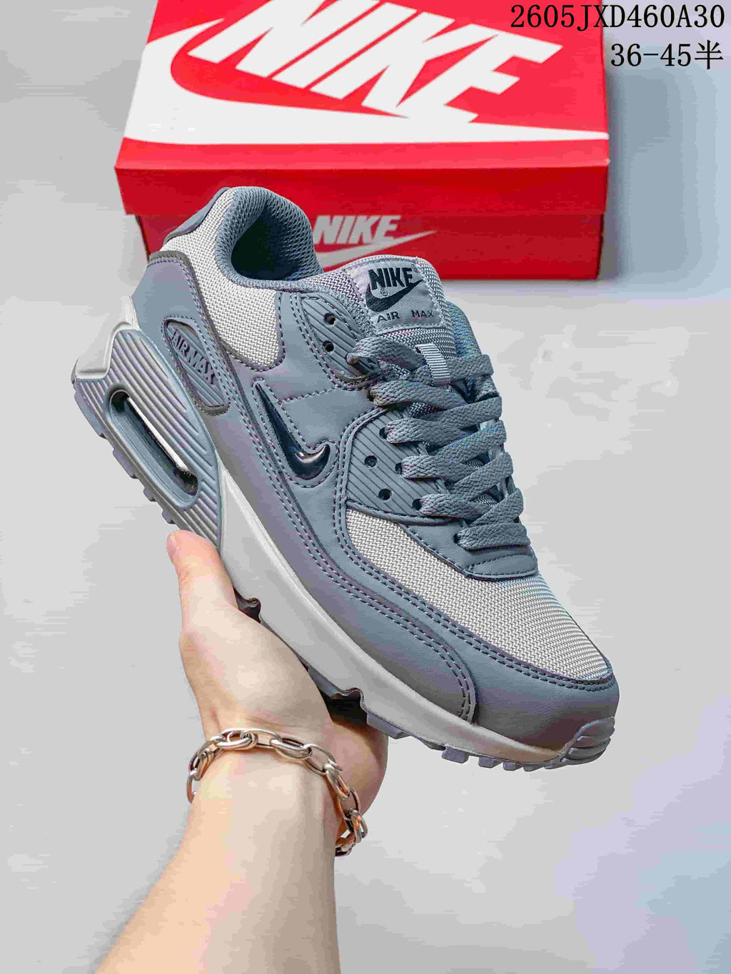Angled view of a grey Nike Air Max 90 sneaker with layered panels