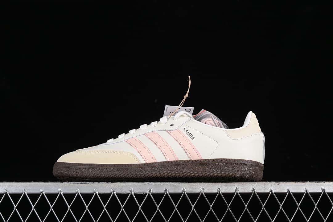 Side view of off-white adidas Samba sneakers with pale pink stripes and a dark gum-style sole