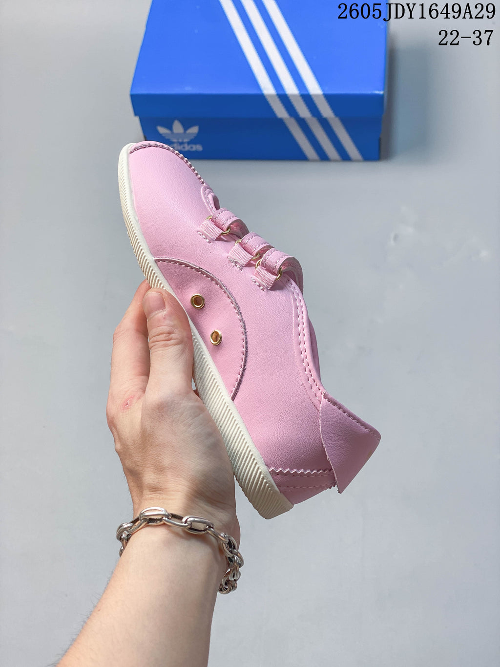 Side view of the pink sneakers showing stitched panels and hook-and-loop straps.