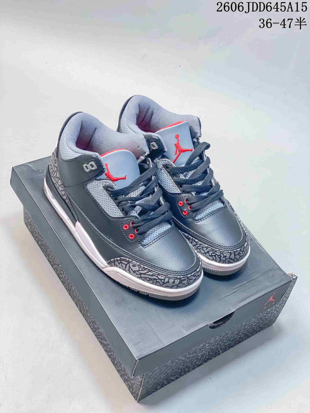 Pair of grey Air Jordan 3 Retro sneakers with red accents and elephant-print overlays, displayed on a shoebox.